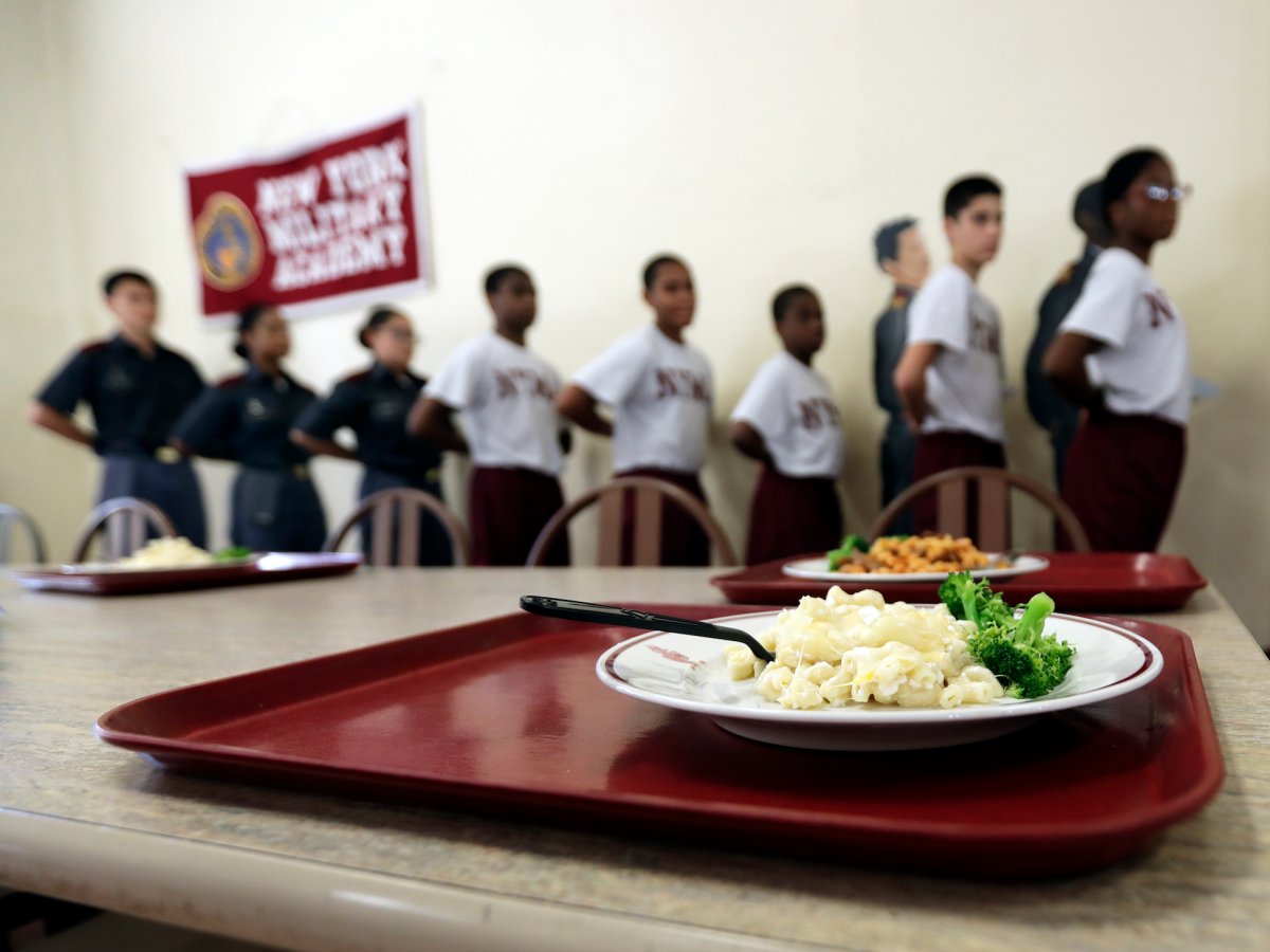 Students stand at attention as they wait to be served lunch in the mess hall.